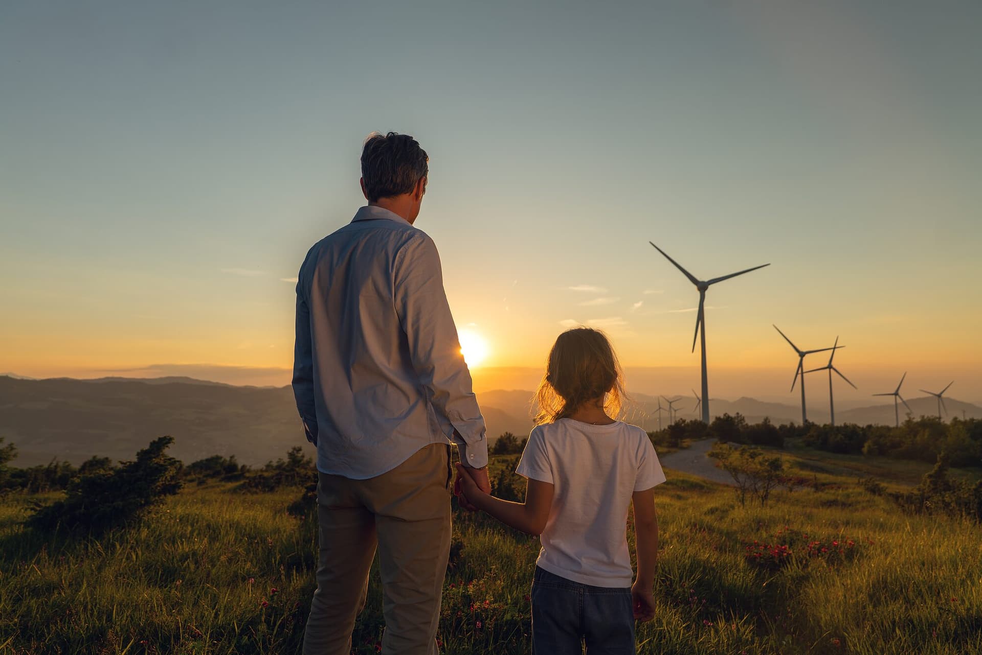 Familie vor Windrädern im Abendlicht
